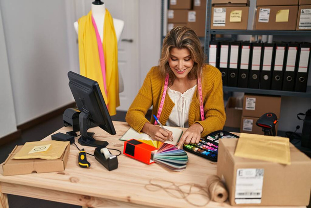 Young blonde woman dressmaker choosing cloth color at designer studio - Photo, Image