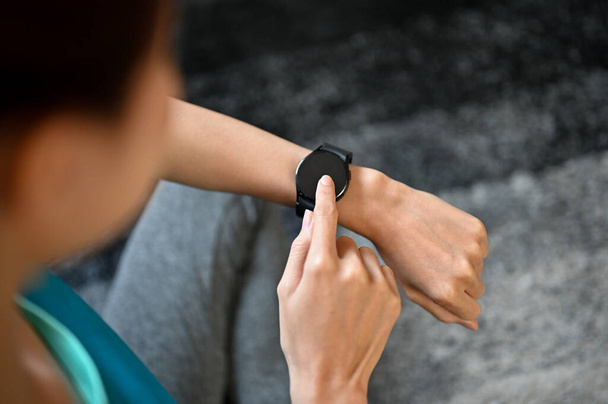 Mulher verificando seu ritmo cardíaco e pulso em seu smartwatch moderno após o treino em casa. Imagem de close-up e vista acima - Foto, Imagem