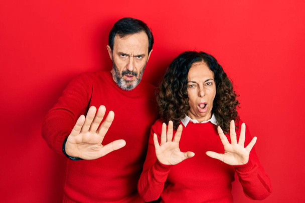 Μεσήλικες ζευγάρι Ισπανίδα γυναίκα και ο άνθρωπος αγκαλιάζει και στέκεται μαζί κάνει στάση χειρονομία με τα χέρια παλάμες, θυμωμένος και έκφραση απογοήτευσης  - Φωτογραφία, εικόνα