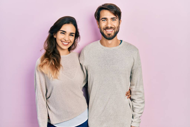Fiatal spanyol házaspár alkalmi ruhát visel, boldog és hűvös mosollyal az arcán. szerencsés ember.  - Fotó, kép