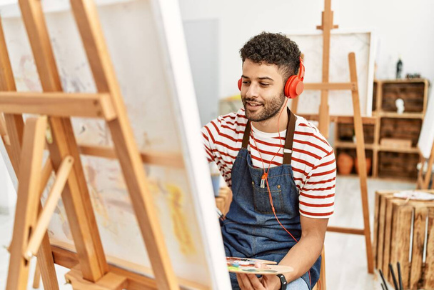 Jeune artiste arabe homme écoutant de la musique dessin au studio d'art. - Photo, image