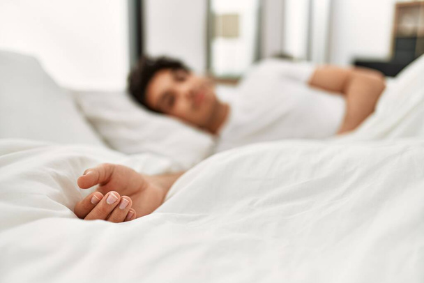 Giovane uomo ispanico dormire sdraiato sul letto in camera da letto. - Foto, immagini