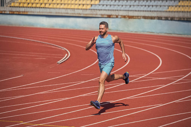 male endurance and stamina. successful sportsman finishing. athlete runner do aerobic or anaerobic load. man start running on stadium. fitness gym outdoor. muscular athletic runner training. sport. - Photo, Image