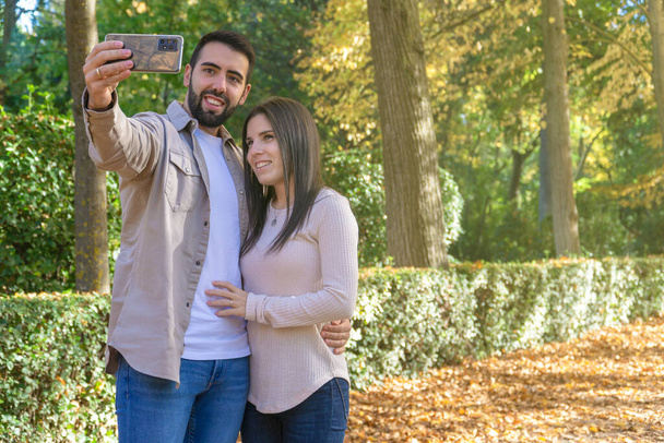 married couple taking a selfie in a park in autumn - Photo, Image