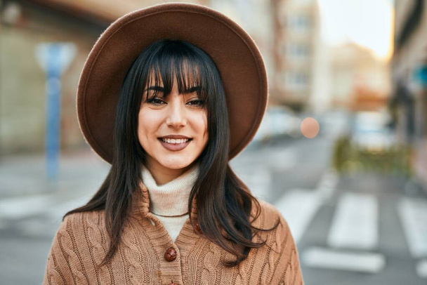 Femme brune portant un chapeau d'hiver souriant à l'extérieur de la ville - Photo, image