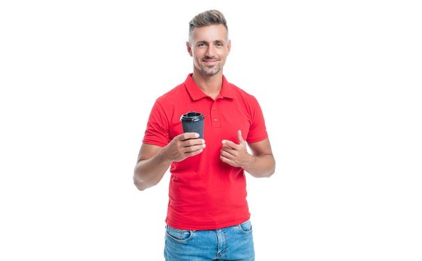Happy barista in casual red tshirt pointing finger at disposable cup with takeaway coffee isolated on white. - Foto, Bild