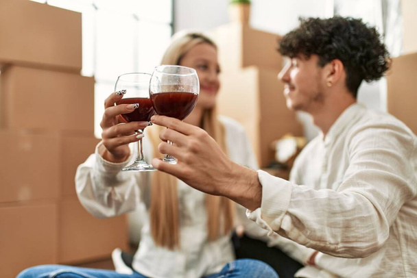 Young beautiful couple smiling happy toasting with red wine at new home - Photo, Image
