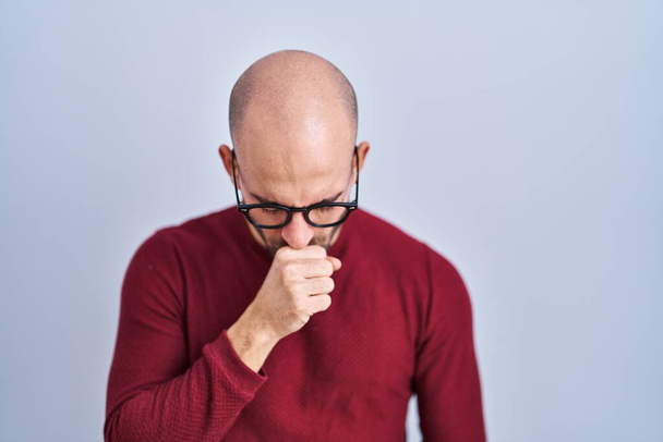 Young bald man with beard standing over white background wearing glasses feeling unwell and coughing as symptom for cold or bronchitis. health care concept.  - Photo, Image