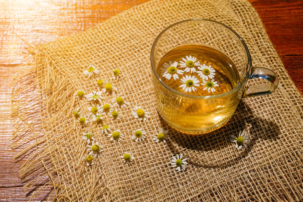 Chamomile tea in a transparent mug with natural small chamomile flowers. High quality photo - Photo, Image