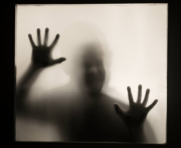 Horror, halloween background - Shadowy figure behind glass of a man - Photo, Image