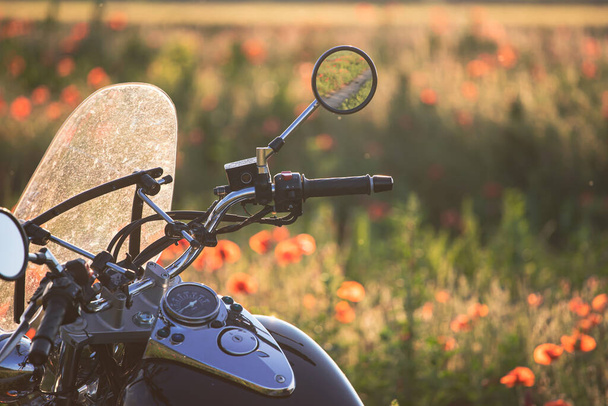 Motorcycle closeup in magic sunset in the poppy field. Travel and sport, speed and freedom concept - Photo, Image