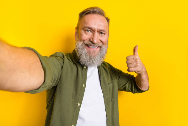 Portrait of cheerful aged man take selfie hand finger demonstrate thumb up isolated on yellow color background. - Foto, Bild