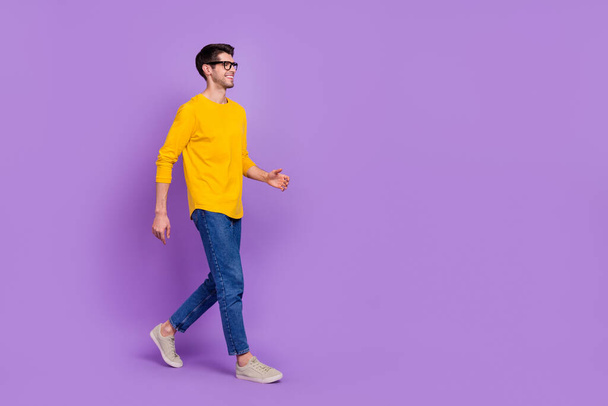 Full size profile side photo of young handsome man go on walk loo empty space isolated on violet color background. - Foto, afbeelding