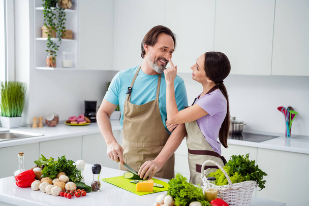 Photo of two peaceful positive partners enjoy cooking together finger touch nose have good mood indoors. - Valokuva, kuva