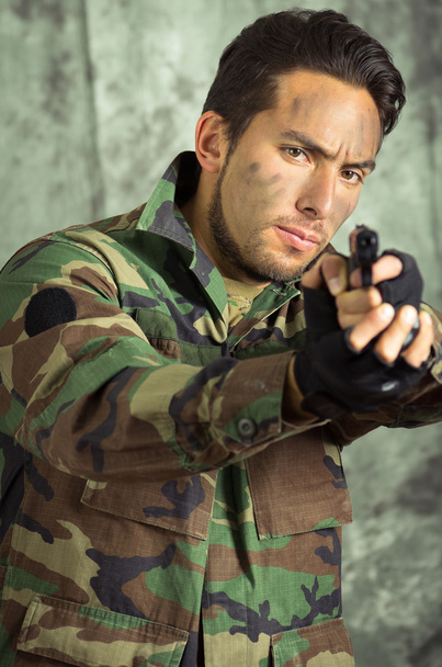 Soldat militanter lateinischer Mann, der eine Waffe zeigt - Foto, Bild