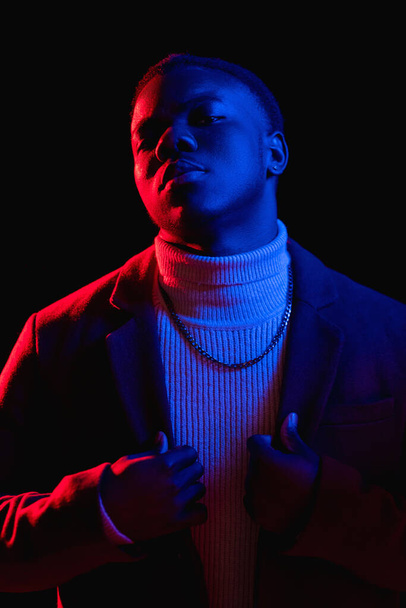 Stylish guy. Neon fashion. Hipster style. Night life. Handsome macho man portrait in trendy clothes colorful red blue light isolated on dark background. - Fotó, kép