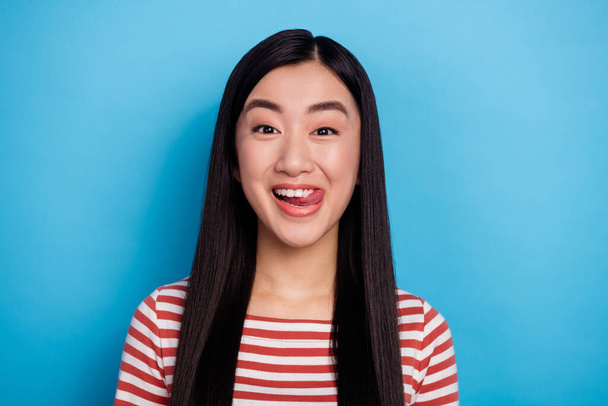 Portrait of charming cheerful indonesian girl tongue lick teeth isolated on blue color background. - Fotografie, Obrázek