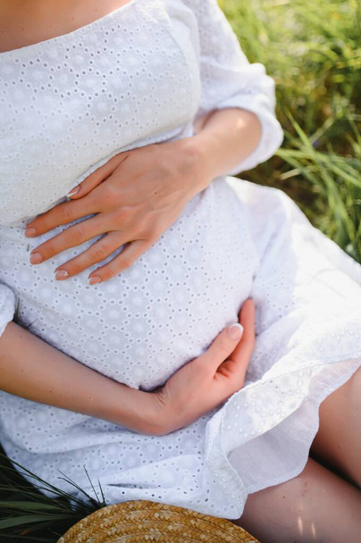 Close-up of pregnant woman with hands on her belly on nature background - Φωτογραφία, εικόνα
