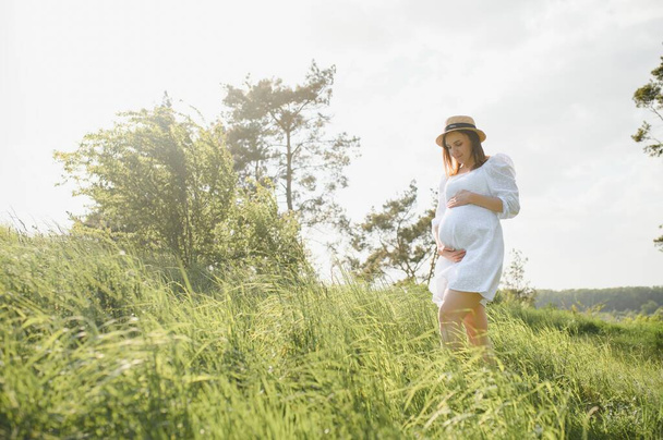 Young happy pregnant woman relaxing and enjoying life in nature. Outdoor shot. Copyspace. - Foto, afbeelding