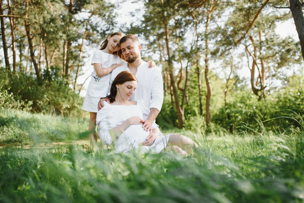 Happy pregnant couple with daughter in summer nature - Fotó, kép