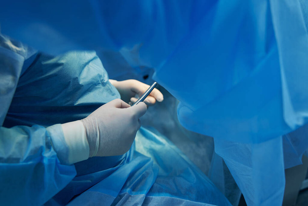 lähikuva gynekologista lateksikäsineissä käyttäen steriiliä instrumenttia hysteroskopiaan - Valokuva, kuva