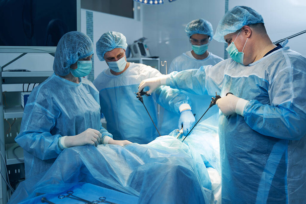 Pečlivý gynekolog pomocí hysteroskopu při léčbě pacienta se svými kolegy pomáhá - Fotografie, Obrázek
