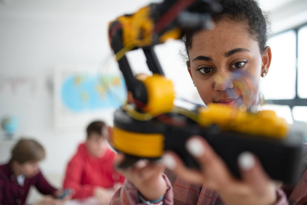 A college student holding her robotic toy at robotics classroom at school. - Фото, изображение