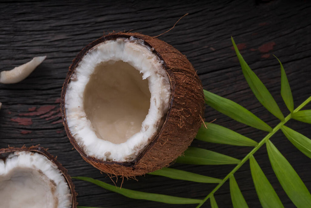 Gesnipperde kokosnoot op een houten achtergrond, bovenaanzicht. Kokosmelk en kokosvlokken zijn tropisch voedsel - Foto, afbeelding