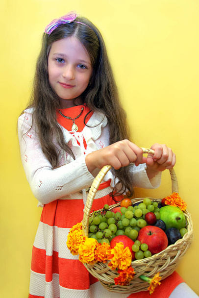 little girl holding a basket with fresh fruits. child with fruits  - Fotoğraf, Görsel