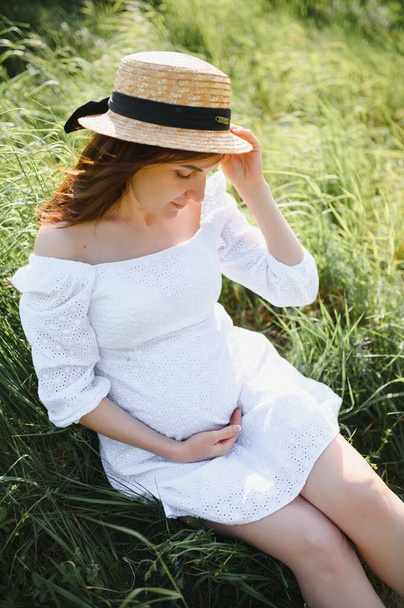 Young happy pregnant woman relaxing and enjoying life in nature. Outdoor shot. Copyspace. - Фото, зображення