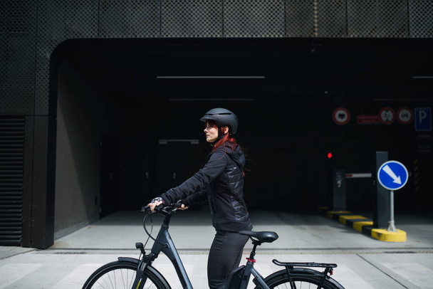 Een portret van zakenvrouw forens op weg naar het werk met de fiets op zoek naar camera, duurzame levensstijl concept. - Foto, afbeelding