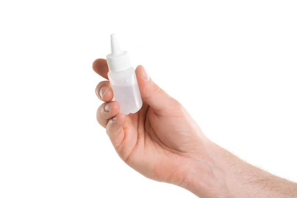 Man's hand holding a white bottle of glue isolated on white background - Zdjęcie, obraz
