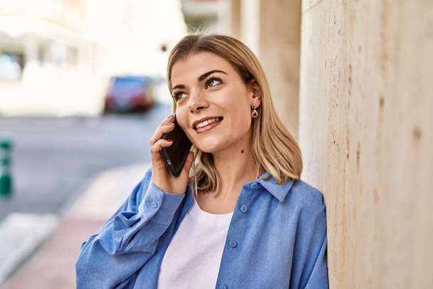 Young blonde girl smiling happy talking on the smartphone at the city. - Fotoğraf, Görsel