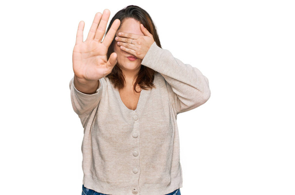 Young plus size woman wearing casual clothes covering eyes with hands and doing stop gesture with sad and fear expression. embarrassed and negative concept.  - Foto, imagen