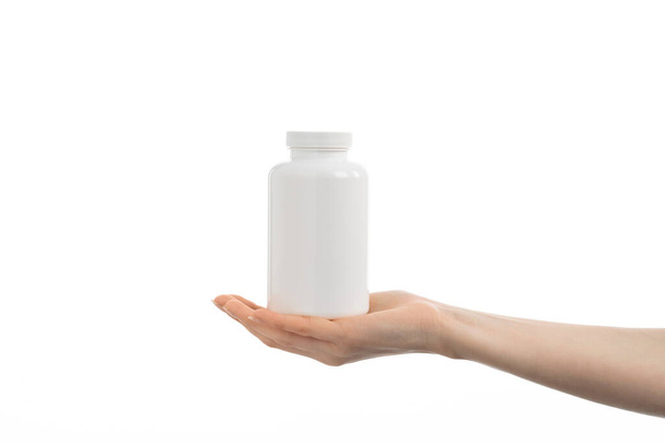 Zbliżenie obraz kobiety trzymającej białą butelkę tabletek lub witamin lub suplementów. - Zdjęcie, obraz