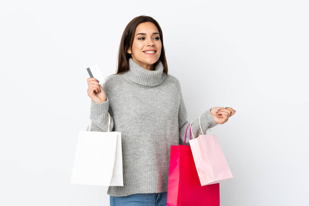 Young caucasian woman isolated on white background holding shopping bags and a credit card - Foto, imagen