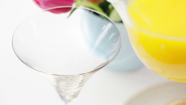 Verter jugo de naranja en un vaso de martini para hacer un cóctel de mimosa - Metraje, vídeo