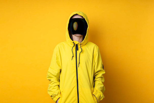 Młoda kobieta w masce gogli cyberpunkowych w żółtej kurtce na żółtym tle. - Zdjęcie, obraz