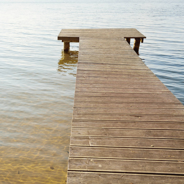 Forest river (lake) on a sunny day. Wooden pier. Water surface and wood texture. Idyllic landscape, rural scene. Nature, ecology, ecotourism, hiking, ecological resort, local tourism - Fotó, kép