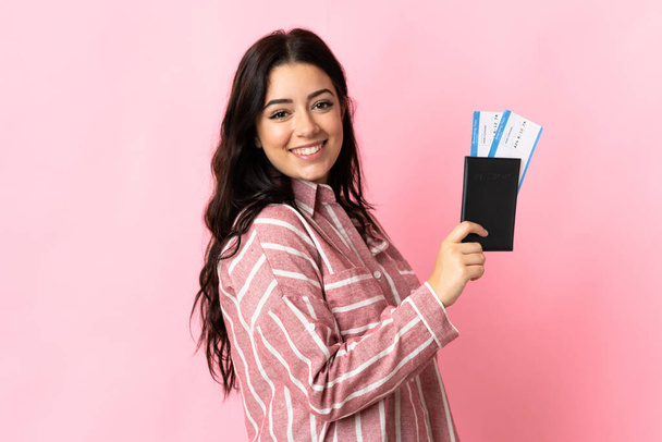 Junge kaukasische Frau isoliert auf rosa Hintergrund glücklich im Urlaub mit Pass und Flugtickets - Foto, Bild