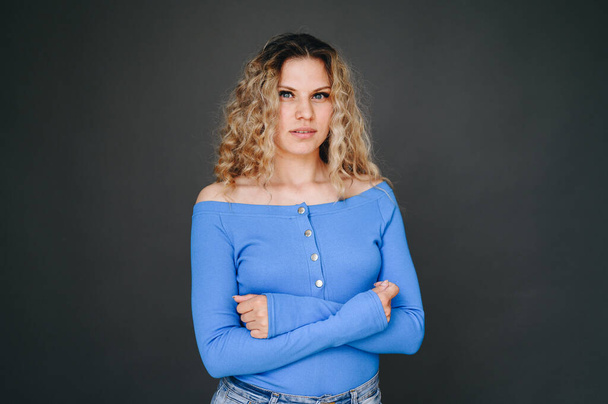 Young Woman In Blue Sweater On Black Background. Woman Curly Folded Her Hands on Her Chest. Eyes full of hope - Photo, image