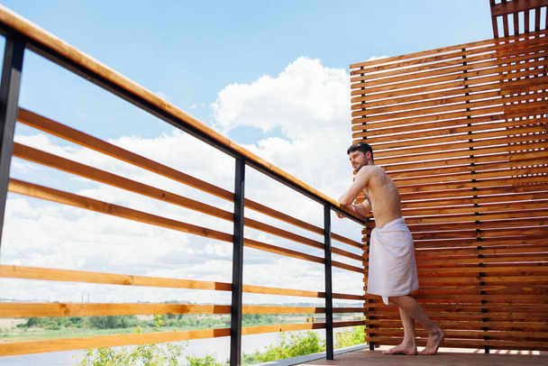 Hezký brunetka muž v ručníku na terase - Fotografie, Obrázek