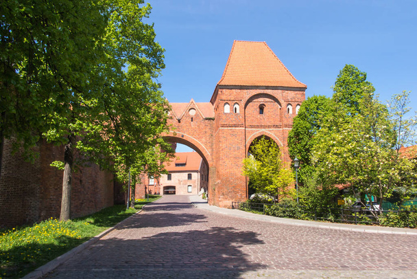 Kilátás a régi városkapu és a gótikus tégla védelmi falak a történelmi belvárosban Torun, Lengyelország. - Fotó, kép
