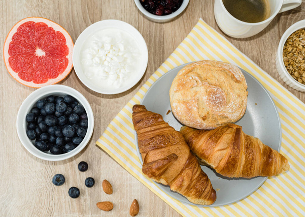 Desayuno saludable. Croissants, bollos, requesón, bayas y frutas y bayas. Vista superior - Foto, imagen