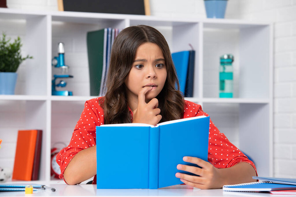 Surprised teenager schoolgirl in class. Back to school. Teenager school girl reading book ready to learn - Foto, Bild