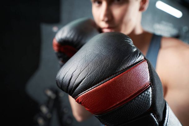 Professional boxer in boxing gloves posing for camera during gym training session - Fotoğraf, Görsel