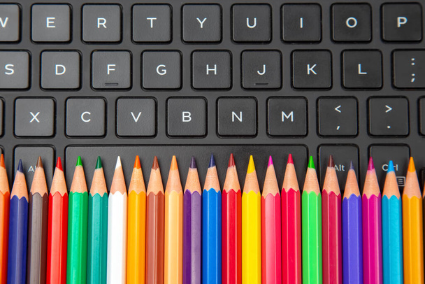 цветные карандаши крупным планом на фоне клавиатуры ноутбука - Фото, изображение