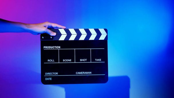 映画クラッパーボード。クルーハンドカメラに対してプラスチックや木製のフィルムスレートボードを保持。ビデオ制作や映画スタジオで使用する映画のクラッパーボードは、映画業界を動作します。乗組員の手にフィルムスレート. - 写真・画像