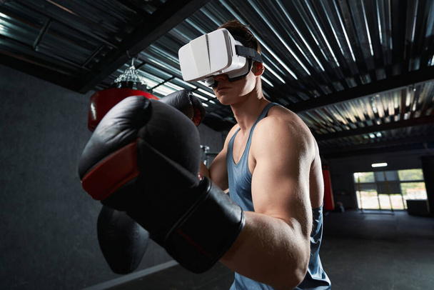 Sportsman in boxing gloves and VR glasses throwing uppercut punch during workout - Fotoğraf, Görsel