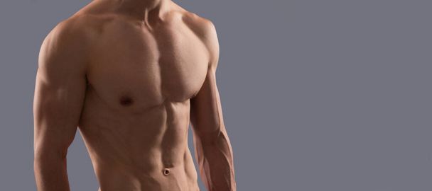 Fitter, athletischer Typ mit muskulösem Oberkörper in Sporthose, grauer Hintergrund, Mann. Mann sexy nackten Oberkörper, Banner mit Kopierraum - Foto, Bild